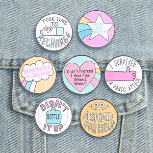 Set of mental health enamel pins with supportive quotes on denim background