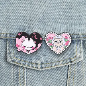 Vue rapprochée détaillée de deux badges en émail de chat en forme de cœur sur du denim