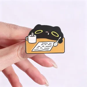 Detailed view of a hand holding a cute black cartoon cat studying enamel brooch pin