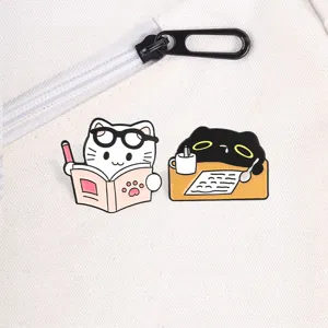 Close-up of cute white and black cartoon cat enamel pins on a white canvas backpack.