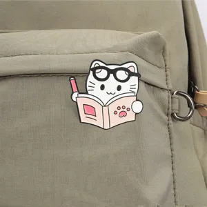 Detailed macro view of a cute cartoon cat reading a book enamel pin on a backpack