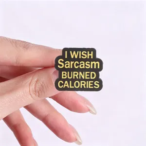 Close-up of black enamel pin featuring a funny sarcasm quote with yellow lettering