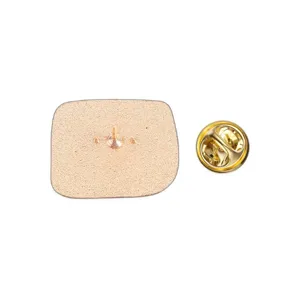 Close-up detail showing the square metal pin badge back with gold butterfly clutch