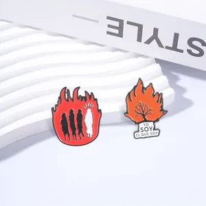 Détail de pins en émail avec arbre en flammes et silhouettes sur vagues