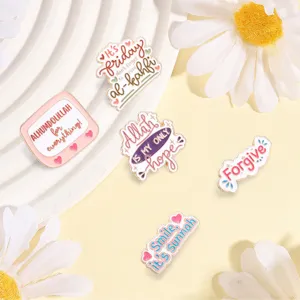 Close-up macro view of colorful enamel pins with Islamic quotes and daisy decorations
