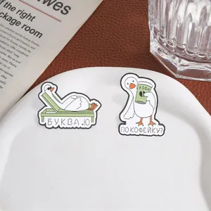 Deux pin's en émail avec des oies russes rigolotes présentés sur une assiette blanche