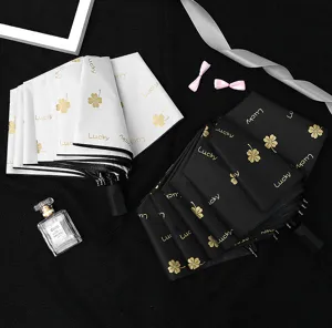 Detail shot of folded black and white umbrellas featuring gold four-leaf clover print