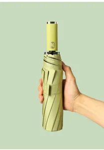 Hand houdt een gevouwen groene automatische paraplu vast tegen een groene achtergrond