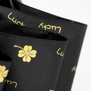 Detail of black anti-UV folding umbrella fabric with gold Lucky and clover print