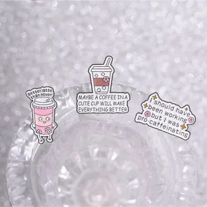 Close-up of funny English coffee enamel pins displayed on a sparkling crystal glass rim