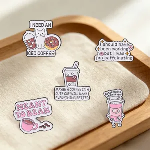 Detailed view of coffee-themed enamel pins with funny English puns on a wooden tray