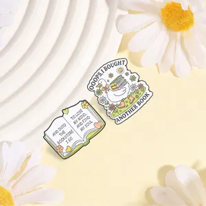 Detail shot of duck and book enamel pins with whimsical text on yellow background