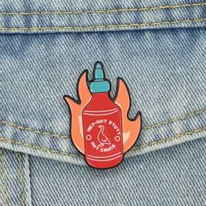 Creative hot sauce enamel pin with duck logo and flames on a denim jacket pocket