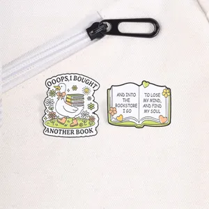 Detailed view of cute duck and open book enamel pins on a white canvas background