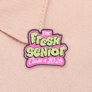 Nahaufnahme des Fresh Senior Class of 2026 Emaille-Pins auf rosa strukturiertem Stoff