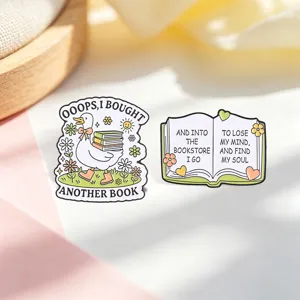Detailed shot of two book-themed enamel pins featuring a duck and an open book quote