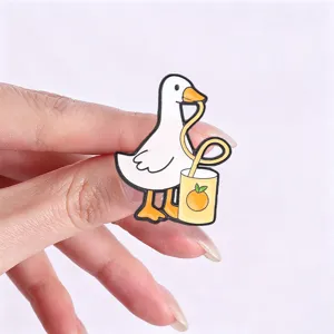 Macro view of a cute cartoon white goose enamel pin drinking orange juice through a straw