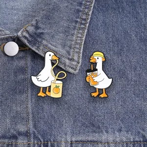Detail view of cute cartoon white goose enamel pins drinking orange juice on denim