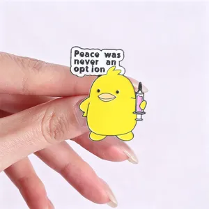 Primer plano detallado de pin de esmalte de pato amarillo con texto de meme humorístico.