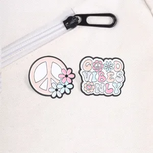 Detail view of retro pink peace sign and daisy enamel pins on a white canvas bag