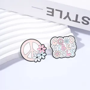 Close-up detail of retro hippie peace sign and good vibes only floral enamel pins