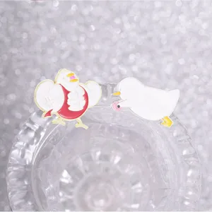 Gros plan de badges en émail de canards amusants posés sur un verre transparent.