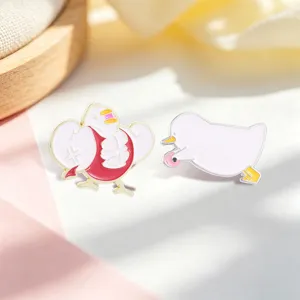 Gros plan de deux épingles en émail de canard blanc avec des motifs de muscle et de bague