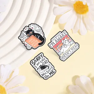 Detailed view of funny cartoon cat enamel pins with humorous English slogans on white tray