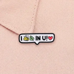 Gedetailleerde detailopname van een 'I believe in you' emaille speld op roze stof