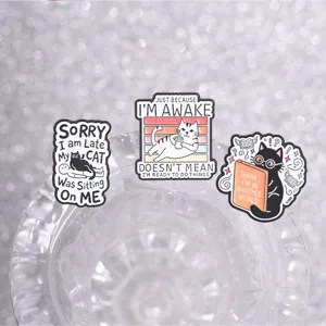 Close-up of three funny cartoon cat enamel pins featuring humorous English slogans.