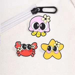 Set of three cute cartoon ocean animal enamel pins displayed on a white fabric backpack