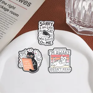 Close-up detail of funny cat enamel pins featuring humorous English quotes on a white plate.