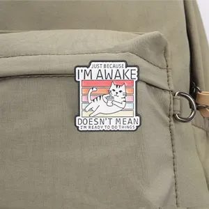 Detailed view of a funny cat enamel pin with lazy quote on a green canvas backpack.