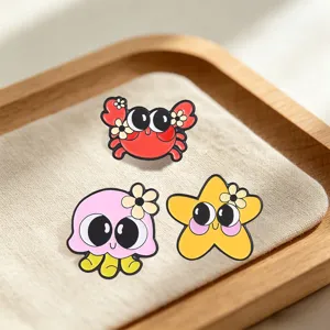 Detail of cute cartoon ocean animal enamel pins on a soft beige fabric background