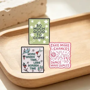 Detail view of inspirational enamel pins with nature and dancing cat designs.