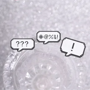 Close-up of retro pixel speech bubble enamel pins with symbols on a glass rim.