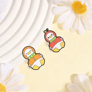 Detailed view of cute fruit-themed duck metal brooches with apple and orange designs.