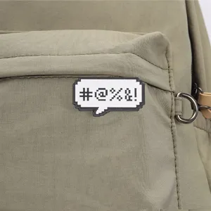Detail view of a pixel speech bubble brooch with symbols on green fabric