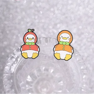 Close-up of cute fruit-themed enamel duck pins featuring apple and orange designs