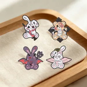 Vue détaillée de quatre épingles en émail esthétiques creepy-cute sur fond de tissu