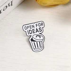 Humorous trash can metal enamel pin with Open For Ideas text on a light surface