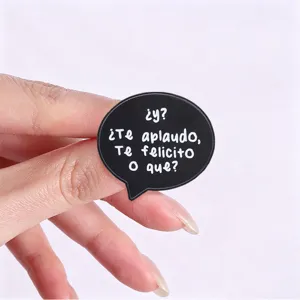 Detailed close-up of a black speech bubble enamel pin with Spanish sarcastic text design