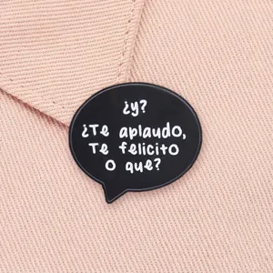 Black speech bubble enamel pin with Spanish sarcasm text on pink fabric detail