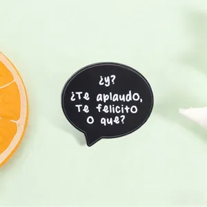 Close-up of a black speech bubble enamel pin featuring funny Spanish text design