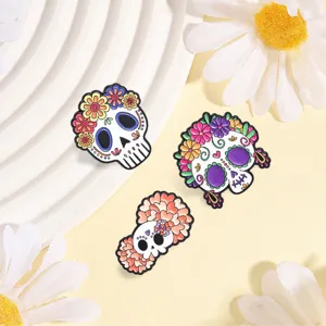 Detailansicht von drei bunten Zuckerschädel-Anstecknadeln mit Blumenmuster für Halloween