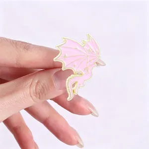 Detailed view of a pink and gold dragon enamel pin featuring small star patterns