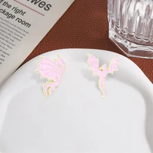Detailed close-up view of pink enamel dragon brooches with gold star wings on a plate