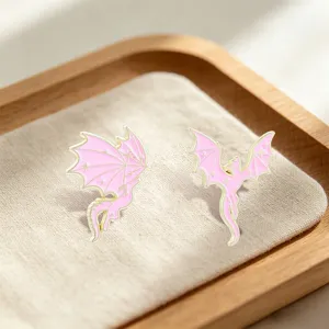 Close-up view of pink and gold dreamlike enamel dragon pins with tiny star details