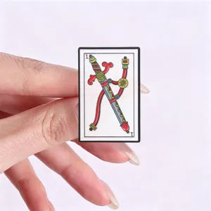 Gedetailleerd overzicht van een vintage tarot zwaard kaart emaille speld in de hand.
