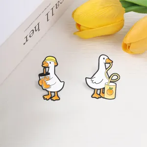 Set of two cute cartoon white goose enamel pins featuring funny drinking poses and yellow cups